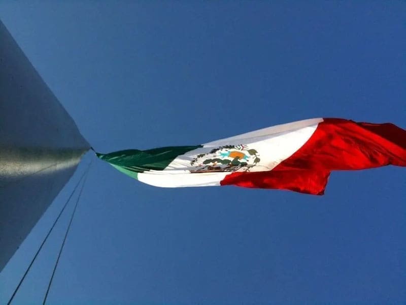 Looking up flag pole Mexican flag.